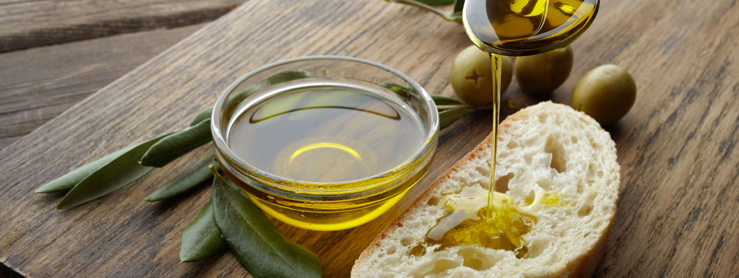 Olivenöl auf Brot neben Glasschale mit Öl